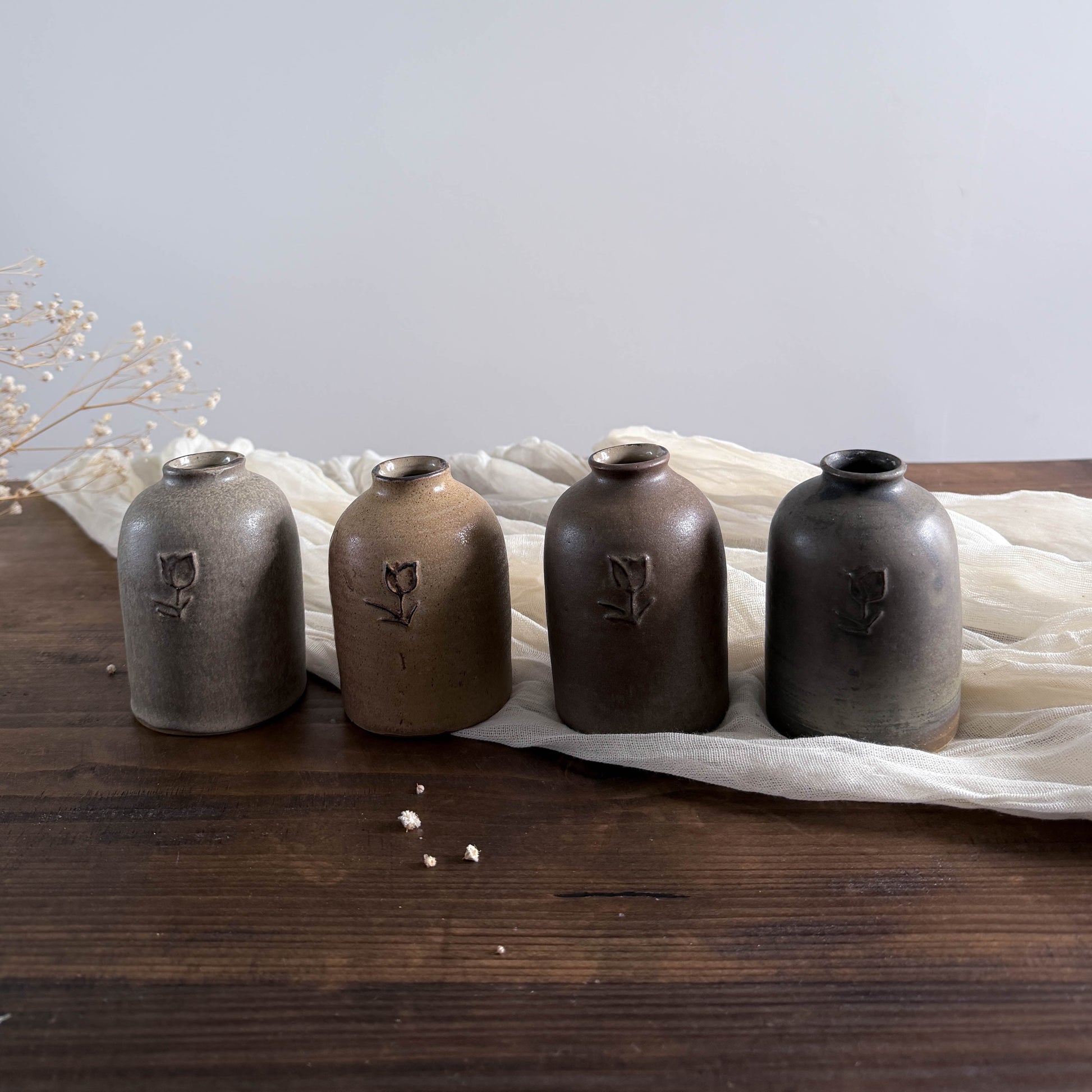 Four ceramic vases with unique markings on a wooden surface and light fabric background